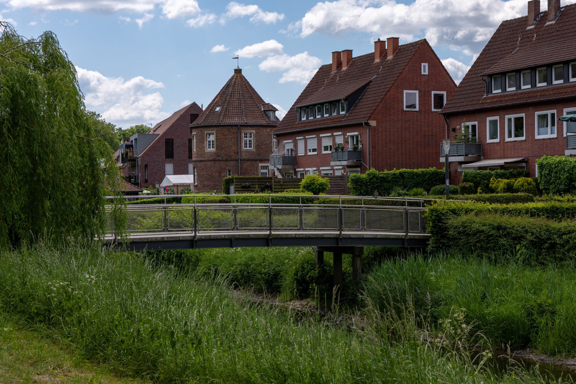 Scenic view of a European village featuring traditional houses and a quaint wooden bridge under a clear sky.